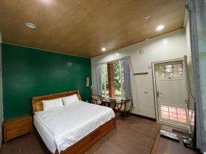 a bedroom with a bed and a green wall at Happiness AIR B&B in Guanshan