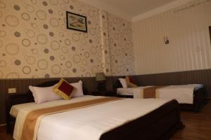 a hotel room with two beds and a wall at Cong Doan Hotel Vung Tau in Vung Tau