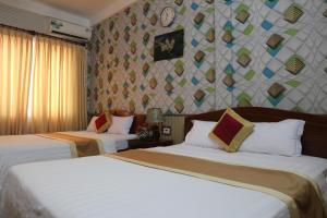 a hotel room with two beds and a wall at Cong Doan Hotel Vung Tau in Vung Tau