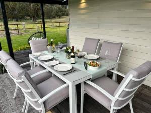 - une table blanche avec des chaises et des verres à vin sur la terrasse dans l'établissement Secluded rural retreat in Southwest WA, à Capel