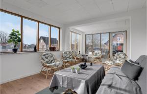 a living room with a table and chairs and windows at 4 Bedroom Gorgeous Home In Aakirkeby in Vester Sømarken
