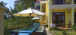 una sombrilla y sillas junto a la piscina en Lakeview Villa Homestay, en Hoi An