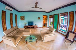 a living room with a couch and a tv at The Sanctuary Langkawi in Pantai Cenang