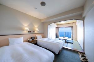 Una habitación de hotel con dos camas y una gran ventana. en Hotel Resorpia Atami, en Atami