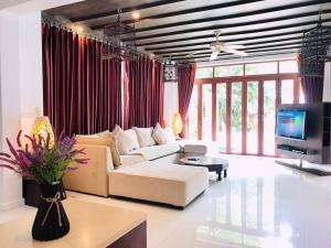 sala de estar con sofá blanco y TV en Amatapura Beachfront Villa 1, SHA Certified, en Ao Nam Mao