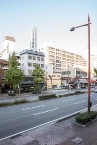 een lege straat in een stad met hoge gebouwen bij Hostel STAND BY ME in Fukuoka