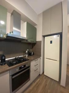 a kitchen with a stove and a white refrigerator at m2 Tbilisi Central Park Apartment in Tbilisi City +17 photos