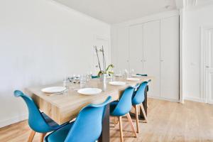 comedor con mesa de madera y sillas azules en Appartement Quartier Le Marais 1 en París