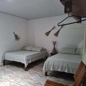 1 dormitorio con 2 camas y TV en la pared en Chalés Paraíso dos Milagres, en São Miguel dos Milagres