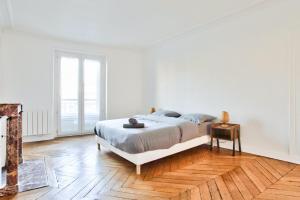 1 dormitorio blanco con 1 cama y suelo de madera en Appartement Quartier Le Marais 1 en París