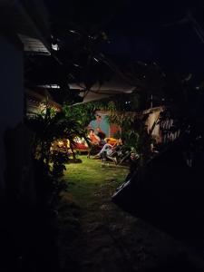 una habitación oscura con gente sentada en sillas en un patio en LA CABANE D'artiste, en Cul de Sac