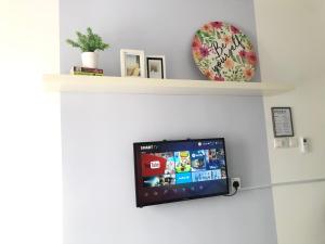TV de pantalla plana en una pared con estantería en Horizon Suites Near KLIA Airport (B) en Sepang