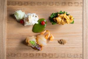 a wooden cutting board topped with different types of food at Arimasansoh Goshobessho in Kobe