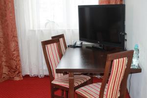 a television sitting on top of a wooden table with two chairs at Hotel Kaprys in Świdnik