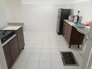 uma cozinha com um frigorífico preto e pisos em azulejo branco em Jannah Homestay Seruling em Putrajaya