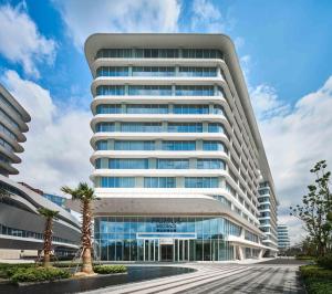 a tall white building with a palm tree in front of it at Primus Residence Shanghai Hongqiao in Shanghai