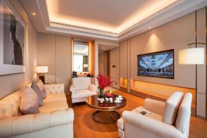 a living room with white furniture and a tv at Landison Plaza HSD Hotel Hangzhou in Hangzhou