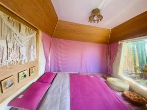 um quarto com uma cama rosa e uma janela em Hoàng Gia Trang em Da Lat