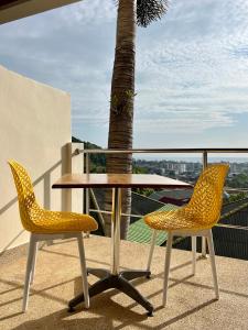 stół i 2 krzesła na balkonie z palmą w obiekcie Mountain Seaview Luxury Apartments w mieście Kata Beach