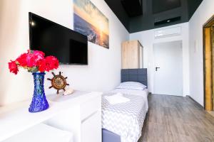 a living room with a tv and a vase with red flowers at Rooms Royal in Stomorska