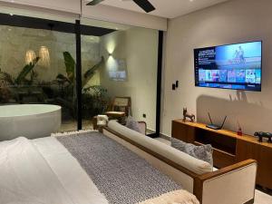 ein Schlafzimmer mit einer Badewanne und einem TV in einem Zimmer in der Unterkunft suite U24 de lujo en chaac tulum in Tulum