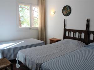 Duas camas num quarto com uma janela e um relógio na parede em Casa Llançà, 2 dormitorios, 5 personas - ES-228-17 em Llançà