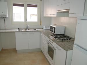 - une cuisine blanche avec évier et four micro-ondes dans l'établissement Apartamento Llançà, 3 dormitorios, 6 personas - ES-228-37, à Llançà
