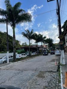 una calle vacía con palmeras y coches aparcados en Apartamento do Walisson, en Guaramiranga