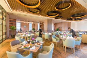 Landison Plaza HSD Hotel Hangzhou في هانغتشو: مطعم فيه طاولات وكراسي وفيه ناس