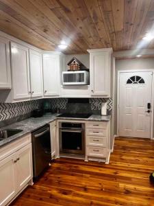 a kitchen with white cabinets and a wooden floor at 2 Bedroom Luxury Home.. Wooden Floors and Ceilings in Dallas