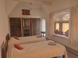 1 dormitorio con 2 camas y ventana en Apani Dhani Eco-Lodge, en Nawalgarh