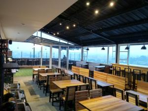 a restaurant with wooden tables and chairs and windows at IDEA's Hotel Jalan Ibrahim Aji in Bandung