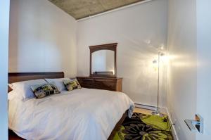 a bedroom with a white bed and a mirror at Les Immeubles Charlevoix - Le 760102 in Quebec City