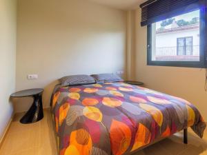 una camera da letto con un letto con un piumone colorato e una finestra di LLEVANTINA 36 - Ático con gran terraza y vistas al mar en Llançà. - ES-228-66 a Llança