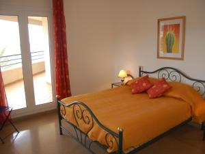 Schlafzimmer mit einem Bett mit orangefarbener Bettwäsche und roten Kissen in der Unterkunft Apartamento Llançà, 3 dormitorios, 6 personas - ES-228-84 in Llança