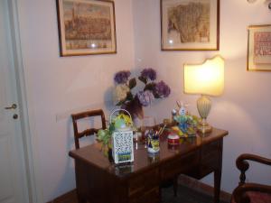 a desk with a lamp and flowers on it at B&B Alle Due Porte in Siena