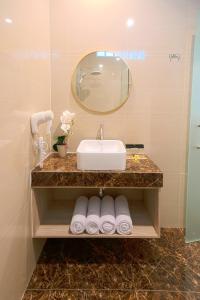 a bathroom with a sink and a mirror and towels at Graha Socio Hotel Nusa Dua Bali in Nusa Dua
