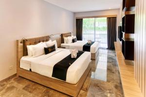 a bedroom with two beds and a television at Graha Socio Hotel Nusa Dua Bali in Nusa Dua