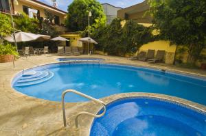 a large blue swimming pool in front of a building at Adventure Inn in San José