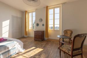 1 dormitorio con 1 cama, 1 silla y ventanas en LaConciergerieJonzac, Maison Côté Vintage avec jardin, en Jonzac