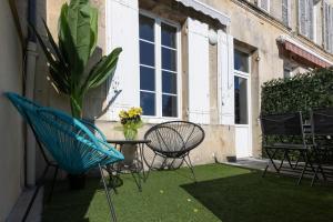 un patio con sillas, una mesa y una maceta en LaConciergerieJonzac, Maison Côté Vintage avec jardin, en Jonzac