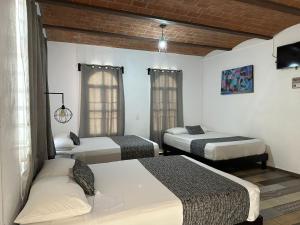 Habitación con 3 camas, TV y ventanas. en Casa Malva Sweet Stay, en Guanajuato