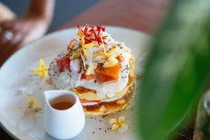 a plate with a pancake with a cup of coffee at Bale Sampan Boutique Bungalows in Gili Trawangan