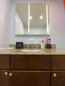 a bathroom counter with a sink and a mirror at Artistic luxury home downtown/train to NYC/AirPort in Newark