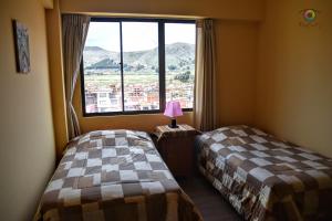 two beds in a room with a large window at solsticio hostel in Copacabana