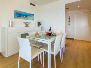 una sala da pranzo bianca con tavolo in vetro e sedie bianche di Apartamento Llançà, 3 dormitorios, 7 personas - ES-228-127 a Llança