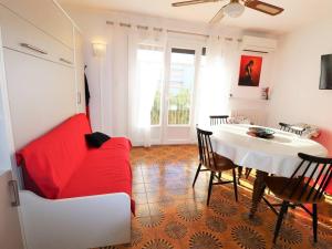 salon z czerwoną kanapą i stołem w obiekcie Grand studio climatisé pour 4 personnes avec parking, à 350m de la mer au Grau-du-Roi - FR-1-307-222 w mieście Le Grau-du-Roi
