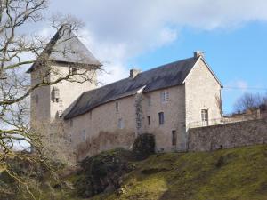 Chambres d'Hôtes L'Hirondelle du Lac في Peyrat-le-Château: مبنى حجري كبير على تلة