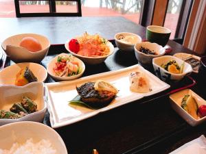 einen Tisch mit Schalen verschiedener Arten von Lebensmitteln in der Unterkunft Marine Blue Yakushima in Yakushima