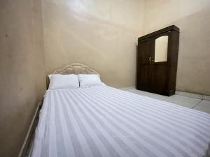 Bett mit weißer Bettwäsche in einem Zimmer in der Unterkunft SPOT ON 92362 Pondokan Tali Super in Parepare
